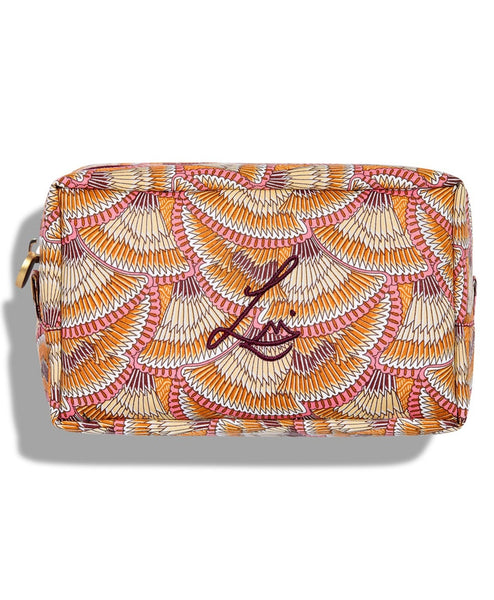 A rectangular beauty bag on a white background. The bag is made using Liberty print fabric which looks like overlapping fans that have brown, beige, orange, white and pink stripes. Lisa Eldridge’s logo is embroidered on the front and the bag has a gold circular zip.