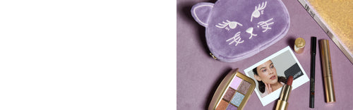 Lisa Eldridge products including Betty Eyeshadow Palette, Velvet Lipstick, Seamless Glide, Kitten Lash and Betty Kitten Pouch, on a purple surface with a book and polaroid photo of Alexa Chung wearing the eyeshadow.