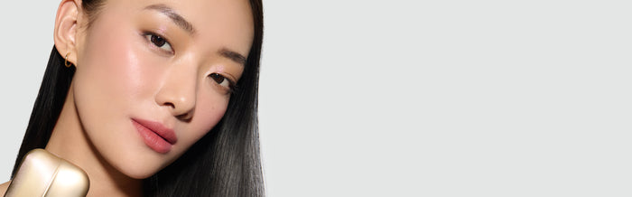 A model's face, wearing Fawn Eyeshadow Palette, with a neutral background holding the Palette, in a banner format