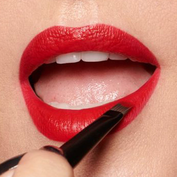 Close-up of Lisa applying Velvet Ribbon lipstick with a brush.