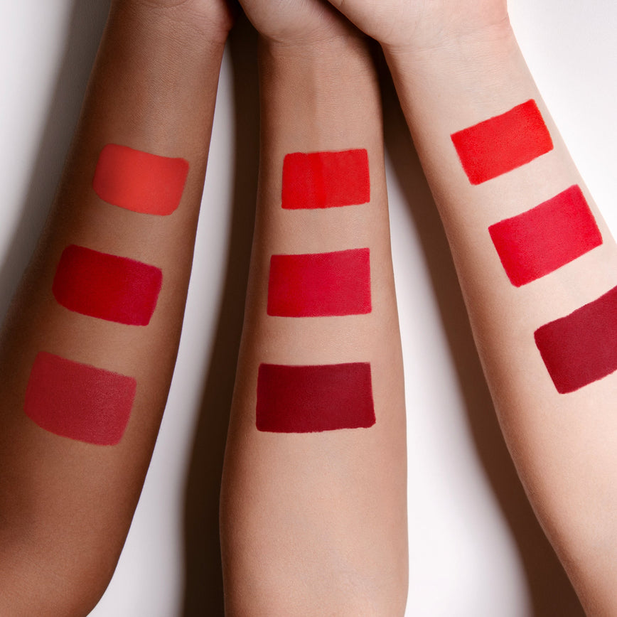 three arms with skin colours ranging from light to medium/deep with swatches of red lipsticks
