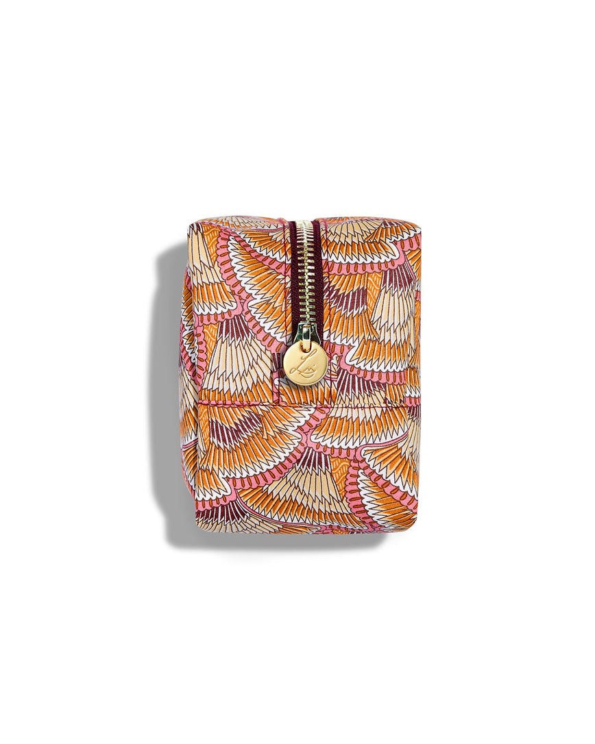Side view of a rectangular beauty bag on a white background. The bag is made using Liberty print fabric which looks like overlapping fans that have brown, beige, orange, white and pink stripes. The bag has a gold circular zip tag with Lisa Eldridge’s logo on it.