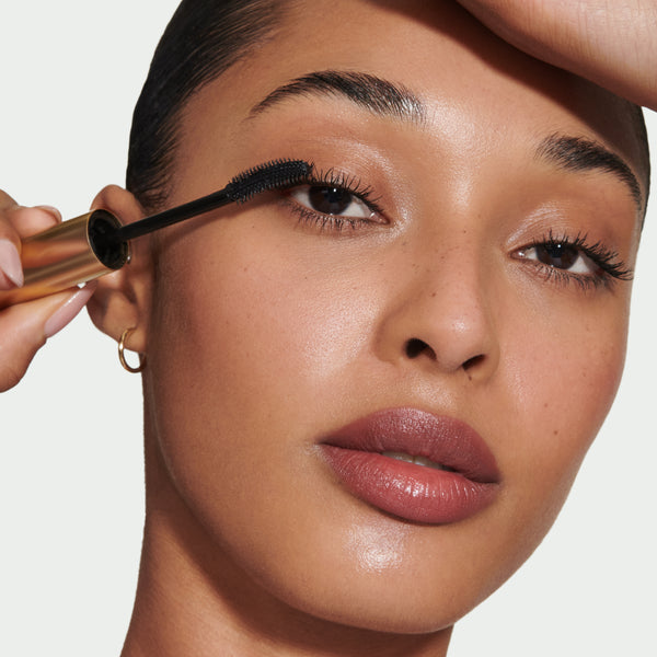Close-up of a model's face, applying Kitten Lash Mascara