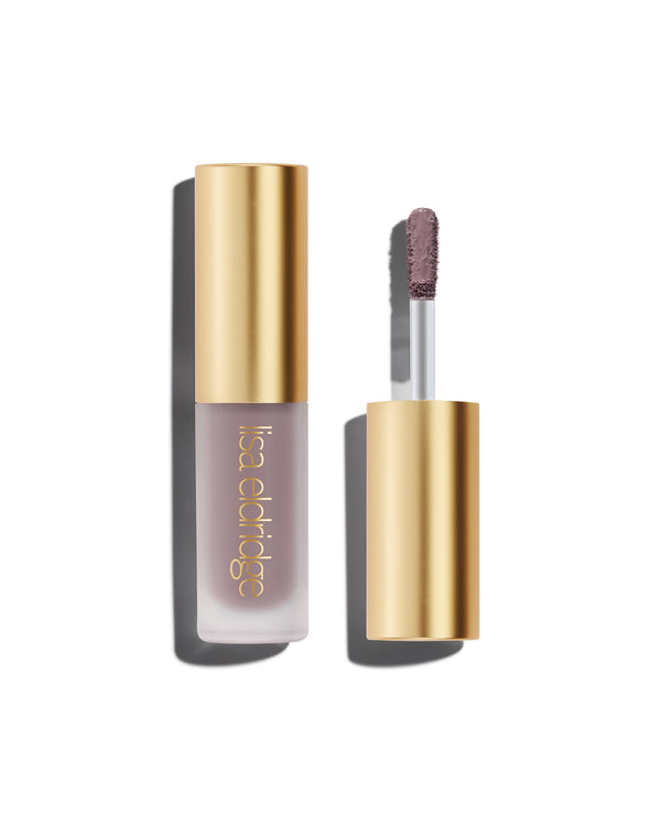 A closed bottle of Lisa Eldridge Liquid Silk Liquid Eyeshadow in shade Maude, with a gold cap containing an applicator wand with product on it, against a white background.