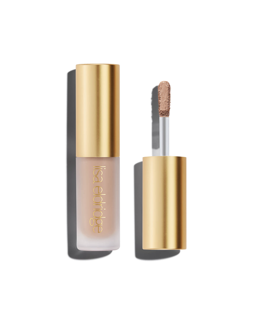 A closed bottle of Lisa Eldridge Liquid Silk Liquid Eyeshadow in shade Paige, with a gold cap containing an applicator wand with product on it, against a white background.