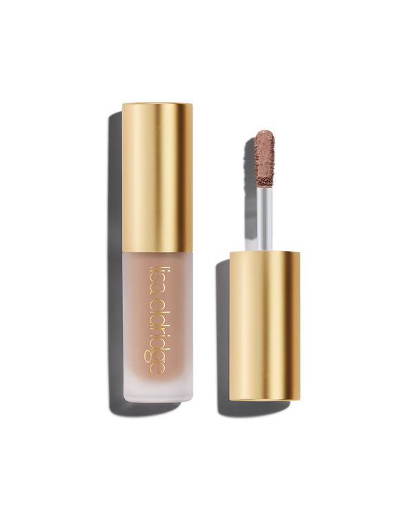 A closed bottle of Lisa Eldridge Liquid Silk Liquid Eyeshadow in shade Silvia, with a gold cap containing an applicator wand with product on it, against a white background.