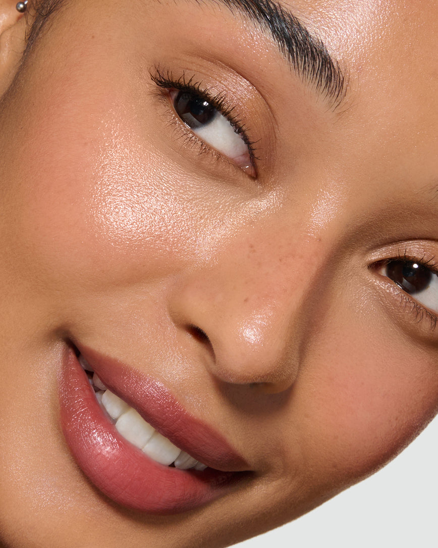 Close-up of a model's face with a neutral background, wearing Velatura Balm in shade Cinnamon Bun