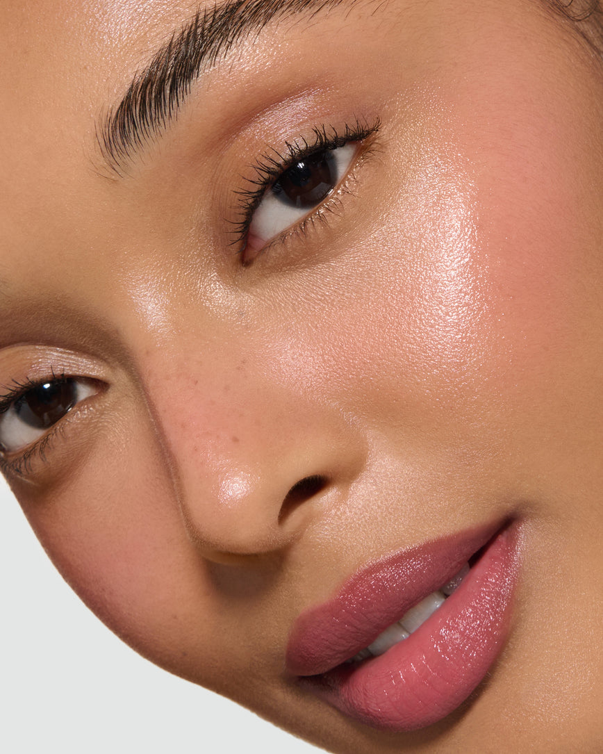 Extreme close-up of a model's face with a neutral background, wearing Rose Madder Velatura Balm on lip and cheeks