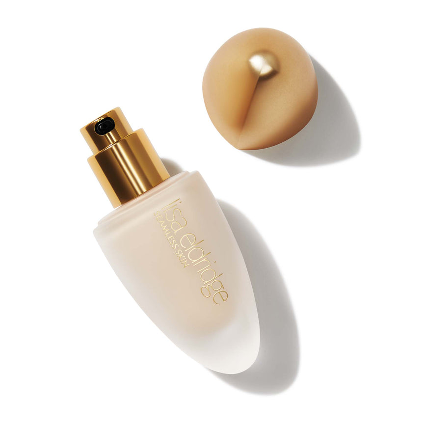 Lisa Eldridge Seamless Skin Foundation in a matte glass bottle with the lid off so you can see the gold pump. The gold lid is next to the bottle.